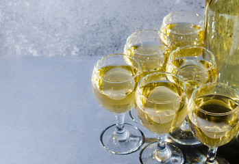 White wine in glass wine glasses, a bottle of wine. Blue background. Copy space
