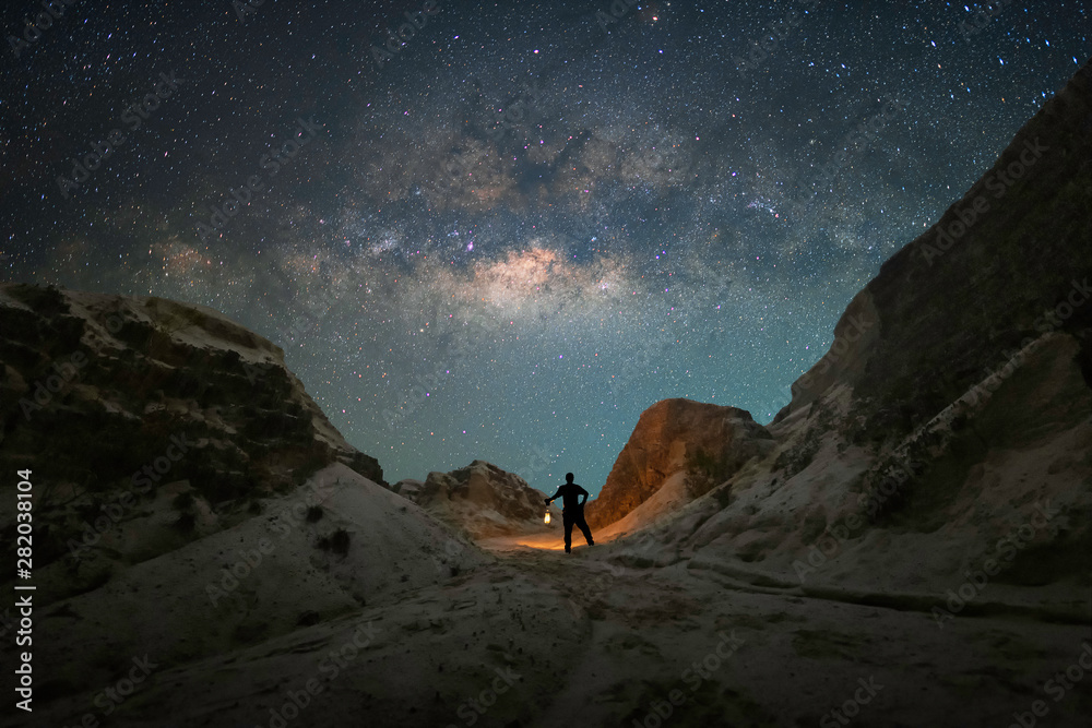 Wall mural a man is standing holds a kerosene lantern of the hill next to the milky way galaxy