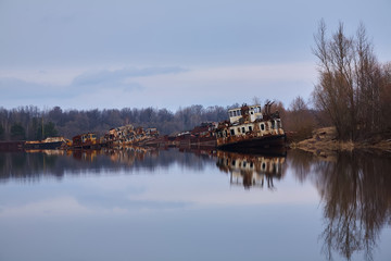 The abandoned river port in Pripyat. Abandoned ships in the river near of Chernobyl. Modern ruins. Radioactive metal