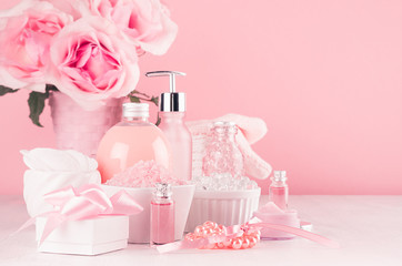 Girlish cute bathroom interior with flowers in pastel pink color - cosmetic products for skin and body care on soft white wood board, copy space.