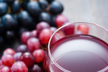glass of red wine and grapes on black wooden table background