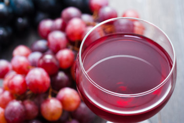 glass of red wine and grapes on black wooden table background