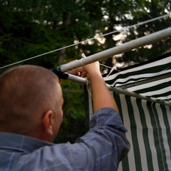 Man strengthening the tent with a rope