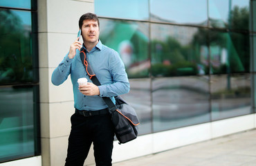 Shot of a handsome commuter taking a phone call while walking outside an office building.