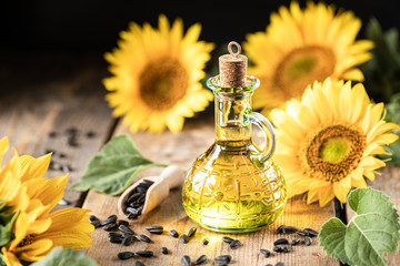 Sunflower oil in a bottle glass with seeds and flowers of sunflower. on blurred background