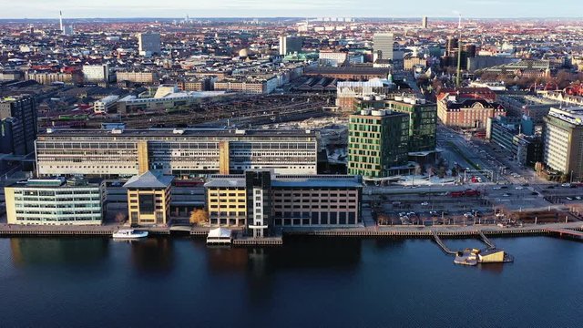 Aerial view above Copenhagen Harbor going South West from Bernstorffsgade along Kalvebod Brygge with a view of Tivoli Gardens in the background and Copenhagen Central Station with trains to and from.