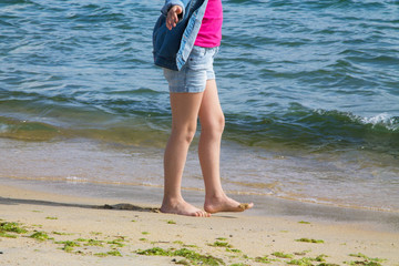 girl's feet by the shore of the beach