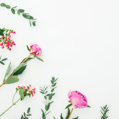 Floral frame with pink peonies, hypericum and eucalyptus branches on white background. Flat lay, top view