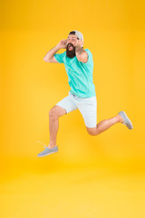 Fototapeta na wymiar Enjoying active lifestyle. Happy guy jumping active to music. Active bearded man in motion on yellow background. Active and energetic hipster dancing to music