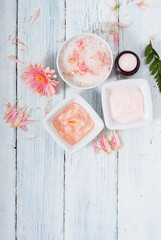 beauty product samples, cosmetic cream, bath salt, liquid soap and pink flower, white wood table