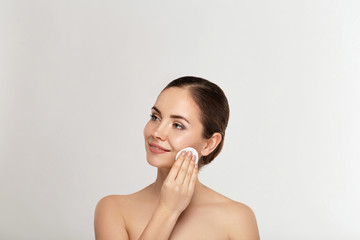 Healthy fresh girl removing makeup from her face with cotton pad. Beauty woman cleaning her face...