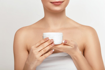 Close up beauty portrait of female face holding and applying cosmetic cream. Skin care. Cosmetology, beauty and spa.