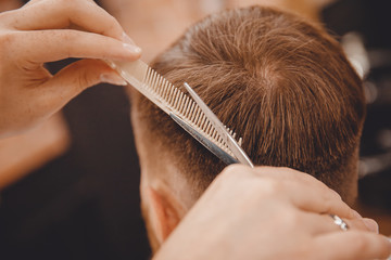 Barber master hairdresser does hairstyle with scissors and comb. Concept Barbershop