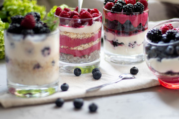 Healthy nutrition Dietary desserts. Glasses are filled with cottage cheese cream, in them chia seeds, raspberries, blueberries, blackberries. Near for background flowers.