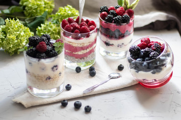 Healthy nutrition Dietary desserts. Glasses are filled with cottage cheese cream, in them chia seeds, raspberries, blueberries, blackberries. Near for background flowers.
