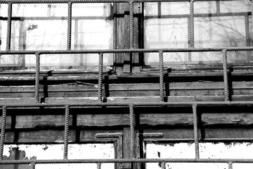 Old window painted white paint behind a rusty bars closeup, black and white