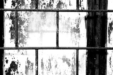 Old window painted white paint behind a rusty bars closeup, black and white