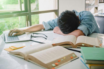 High school or college sleep while sitting at table. Group students studying and reading with books in library. Students helps friend catching up and learning tutoring. education concepts