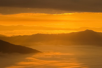 Mountain view misty morning of top hills around with sea of mist in valley and yellow sun light with cloudy sky background, sunrise at Pha Tang, Chiang Rai, northern of Thailand.