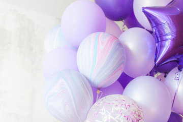 Fototapeta na wymiar Flying purple and violet balloons on light gray background while celebration. Birthday background with ballons.