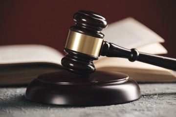 Law concept - Open law book with a wooden judges gavel on table in a courtroom or law enforcement...