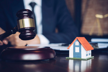 Real Estate Law concept. Gavel on sounding block in hand's Male judge at a courtroom, working for the insurance compensations. report the case on table in modern office.
