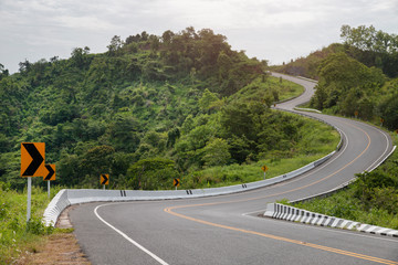 Curved asphalt road with sign curves in the mountains.