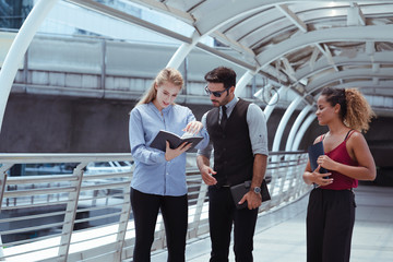 Group of business people checking date of customer appointment on notebook while walking in the city