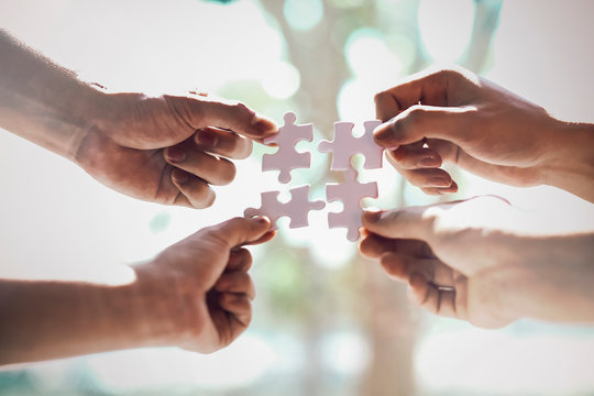 Closeup hand of business people connecting jigsaw puzzle with sunlight effect, Business solutions and represent team support and help concept, success and strategy concept