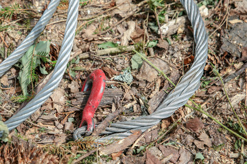 metal cable thick braided red hook retainer close-up against the background of the ground sawmill