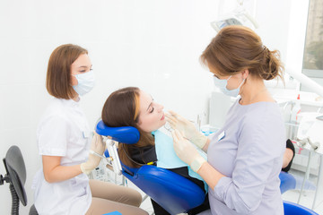Fototapeta premium a woman dentist with an assistant treats a tooth to a woman in a modern dental clinic
