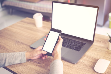Business woman using laptop computer do online activity and holding phone on wood table.