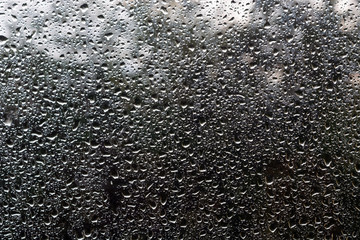 water drops on glass against the sky and trees.