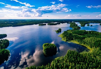 Aerial view of blue lakes and green forests on a sunny summer day in Finland from above