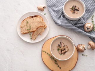 Obraz na płótnie Canvas Mushroom cream soup in white bowl with bread on the table. Delicious cream soup with champignon mushrooms.