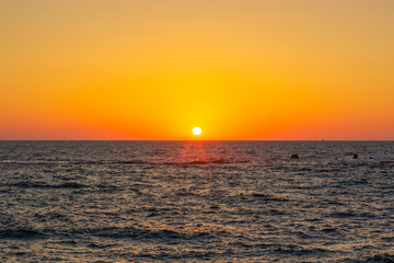 idyllic peaceful natural background scenic landscape photography of vivid orange sunset above Caribbean sea wavy water surface with small ship on horizon, copy space  