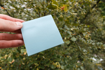 male hand holding a blank sticker. square paper with space for text in the hand of a young man, close-up. sticky note on a hand.