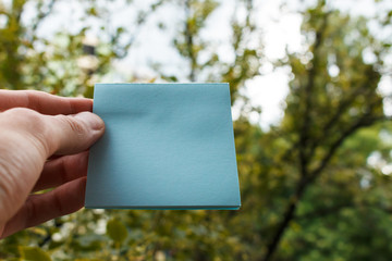 empty sheet of square blue paper in a man’s hand.