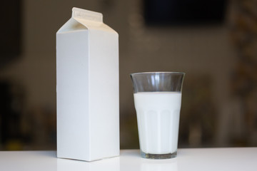Carton box and glass of milk on table in kitchen