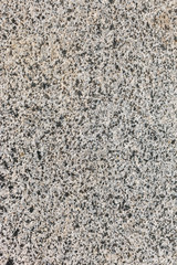 background of mountain granite. Polished granite rock texture with black dots and yellow dust, vertical image.