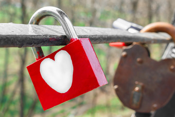 red love padlock with hand-drawn white heart. Colored love padlock is hanging on the bridge for love. Valentine`s Day ritual concept. love padlock&nbsp;is a&nbsp;padlock&nbsp;which&nbsp;sweethearts&nbsp;lock to a&nbsp;bridge