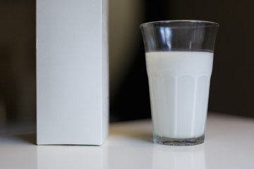 Carton box and glass of milk on table in kitchen
