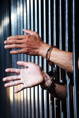 Obraz premium hand of prisoner in steel jail background