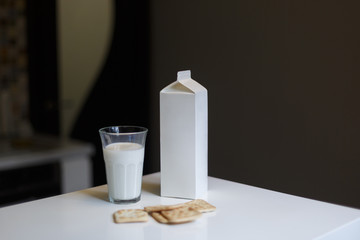 Carton box and glass of milk on table in kitchen