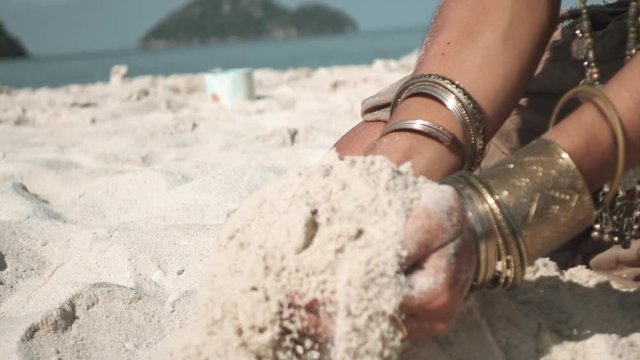 Isolated woman hands with ethnic decorations picking sand in palm and dissolve sand through fingers in slow motion