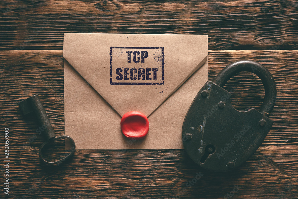 Wall mural top secret documents in envelope, rusty padlock and a key on a wooden table flat lay background. con