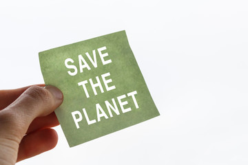 fingers of a teenager hold sticker with call to save the planet. white inscription save the planet in the male hand. The Concept of ecology