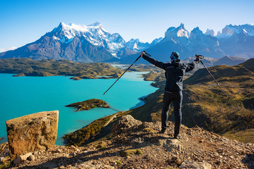 Hiker at mirador condor enjoying amazing view of Los Cuernos rocks and Lake Pehoe in Torres del...