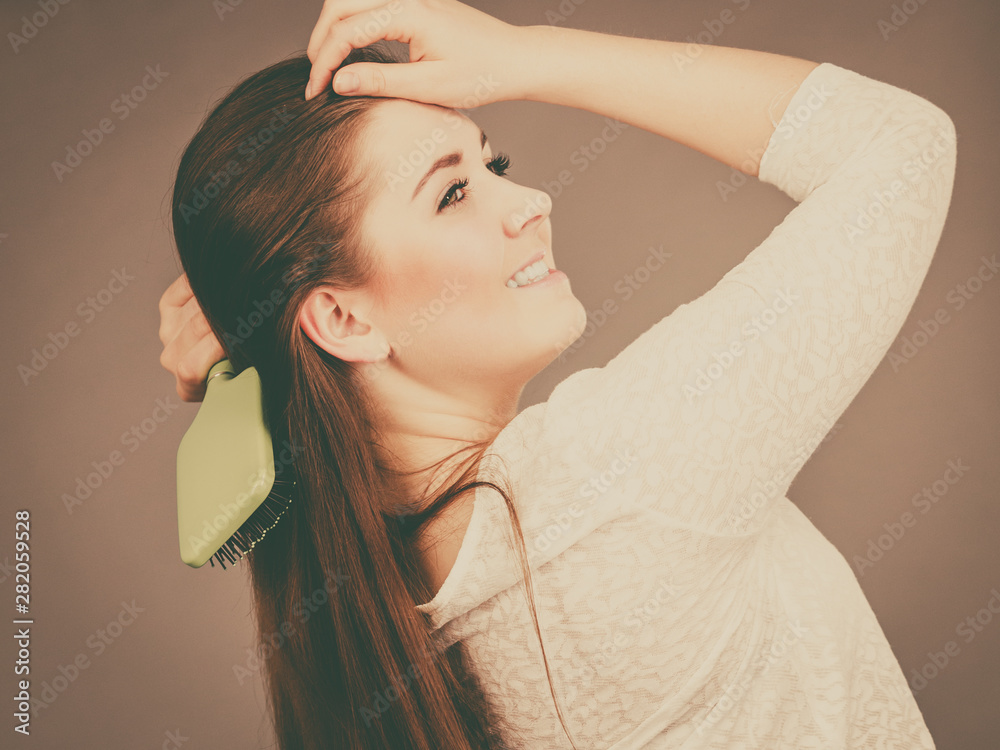 Wall mural Happy woman brushing her hair