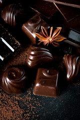 Assortment of dark, white and milk chocolate stack, chips. Chocolate and coffee beans on rustic wooden sacking background. Spices, cinnamon. Selective macro focus. Chocolates background. Sweets